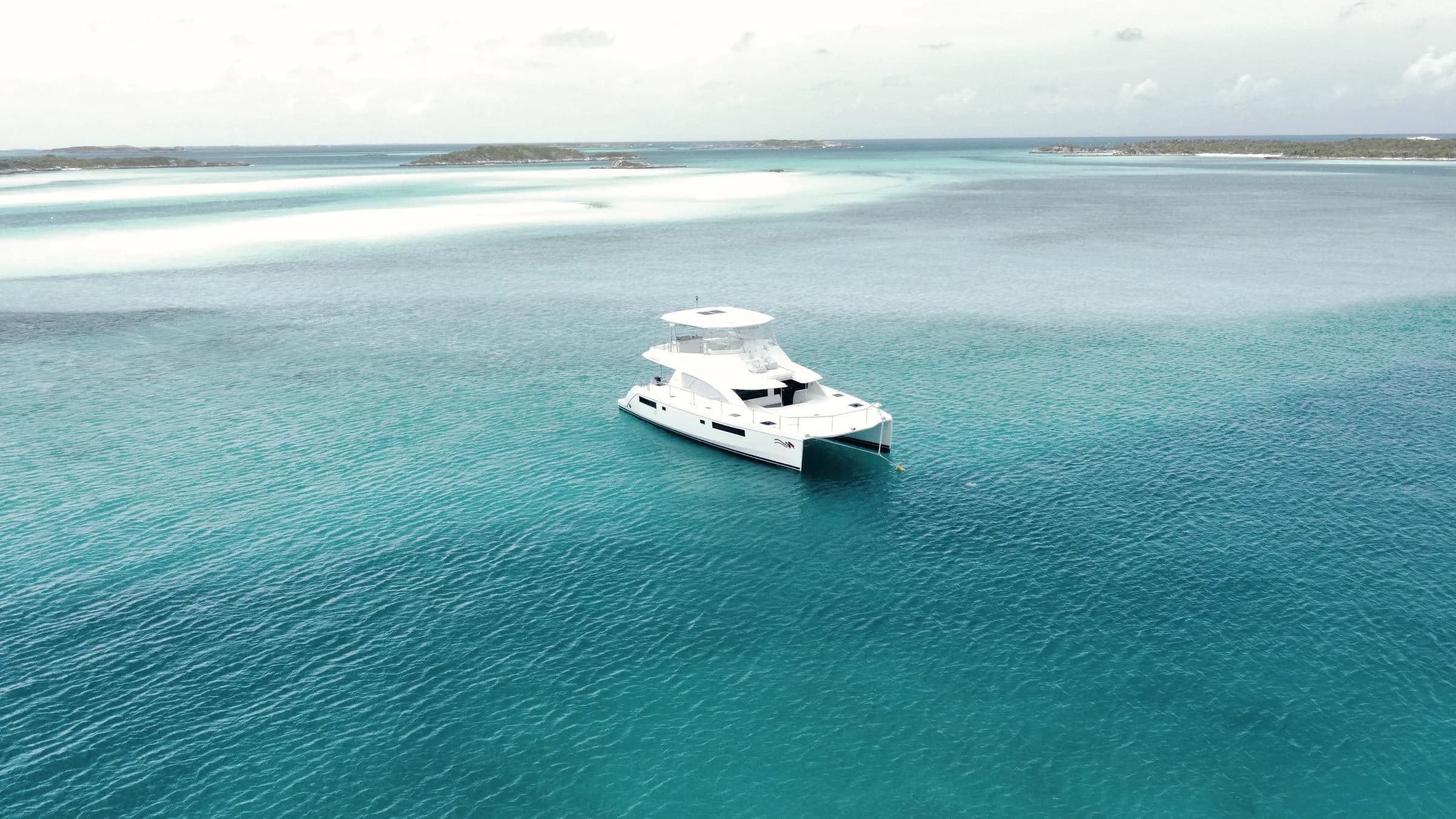 Iate catamarã ancorado em água azul transparente, visto do alto